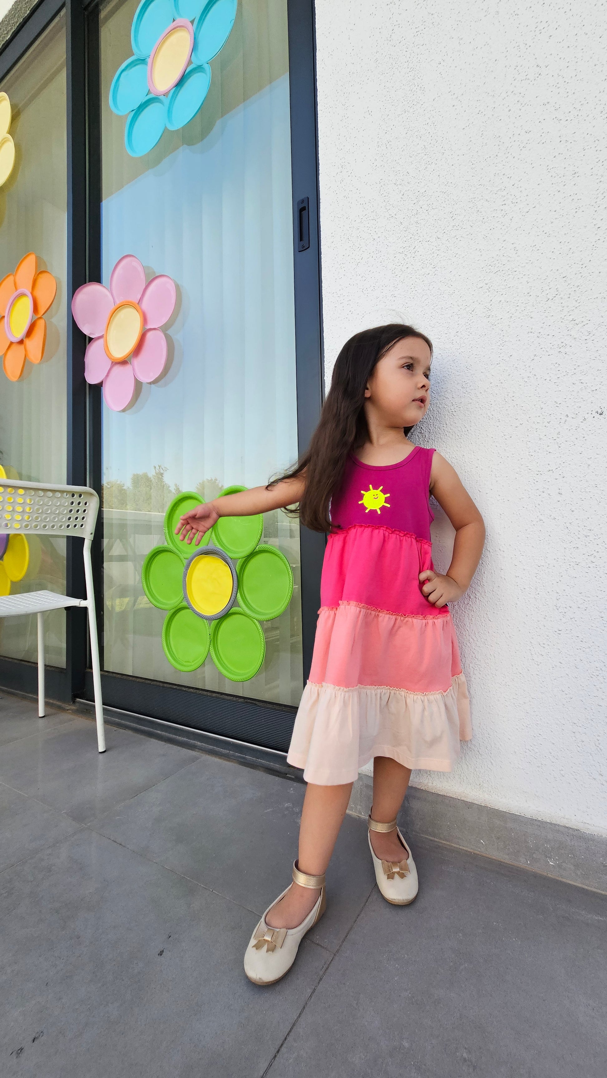 Gypsy Dress 🌞 worn by a girl, showcasing vibrant colors and playful design against a flower-decorated background.