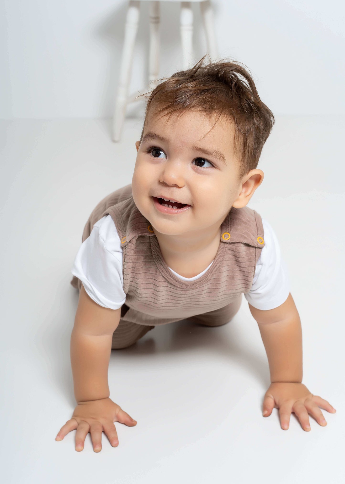 Organik kahverengi bebek tulumu ile emekleyen mutlu bebek, rahat giyim deneyimi.