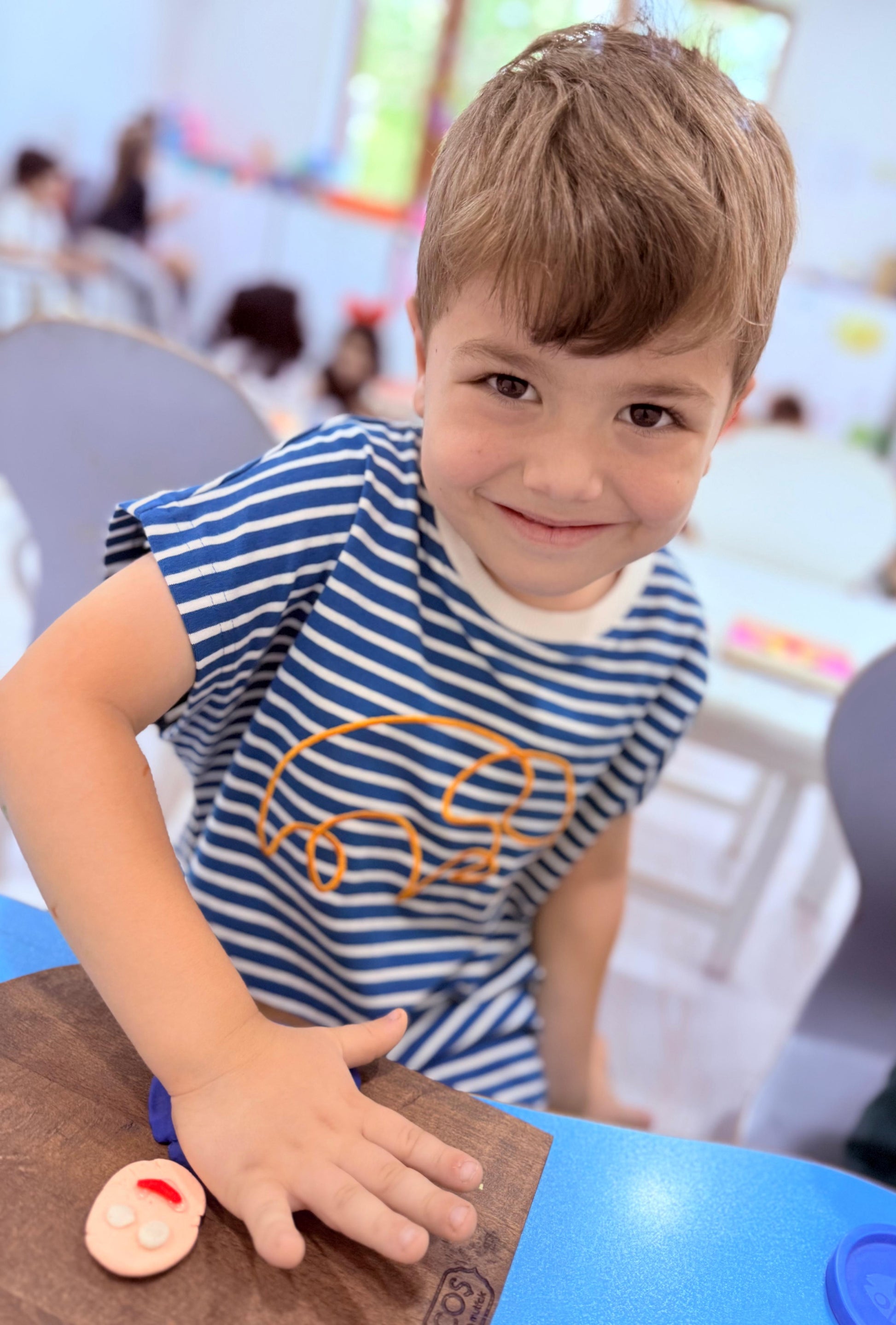erkek çocuk derin mavi tişört giyen gülümseyen çocuk, sanat etkinliği yapıyor