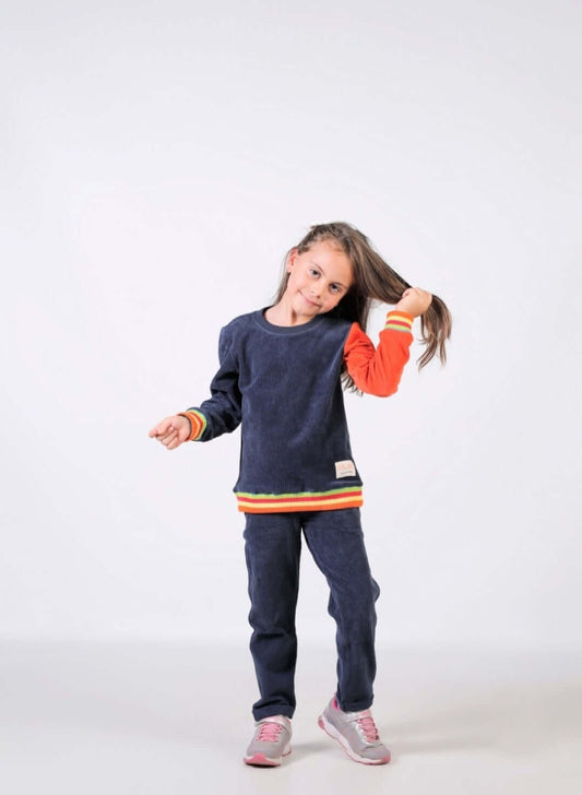 Kız çocuk sweatshirt giymiş bir kız, şık ve rahat görünümüyle neşeyle poz veriyor.